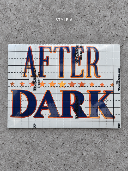 After Dark Style A vinyl decal with Cayenne Orange outline and Glossy Blue lettering under transfer tape on grey concrete