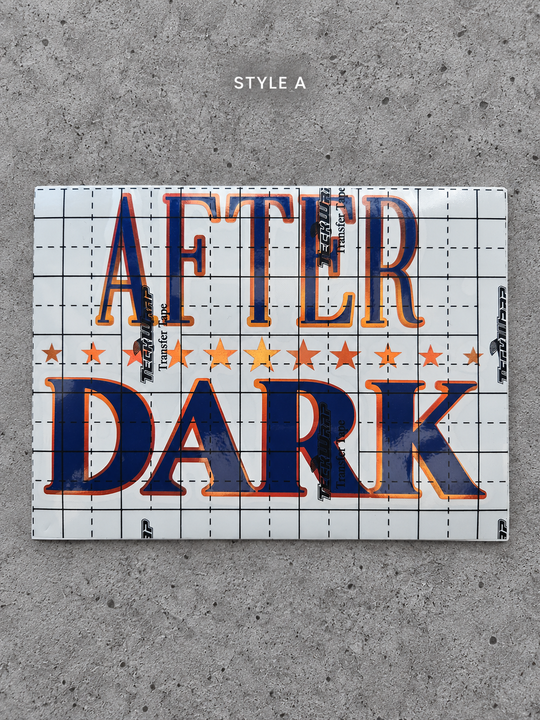 After Dark Style A vinyl decal with Cayenne Orange outline and Glossy Blue lettering under transfer tape on grey concrete