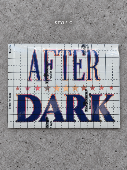 After Dark Style C vinyl decal with Rose Gold outline and Glossy Blue lettering under transfer tape on grey concrete