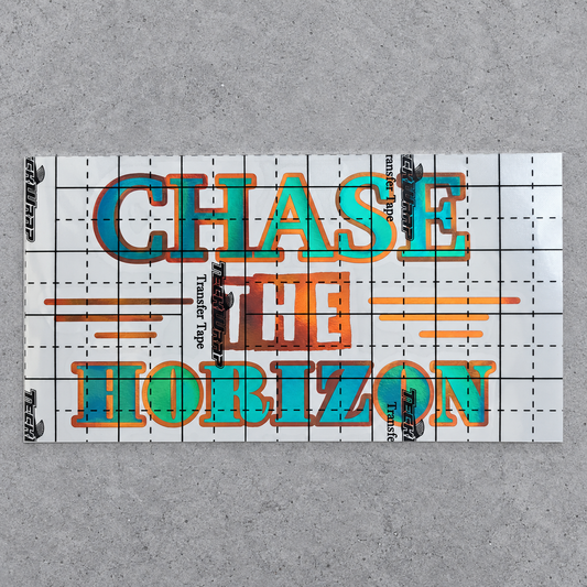 Chase the Horizon green and orange vinyl decal under gridded transfer tape on grey concrete