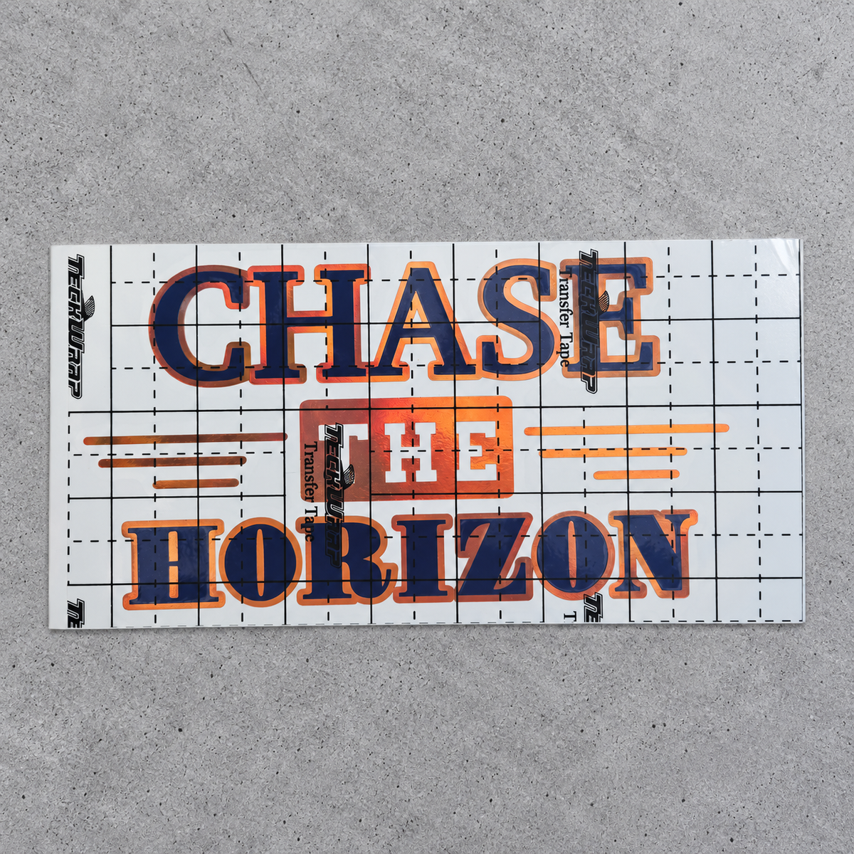 Chase the Horizon blue and orange vinyl decal under gridded transfer tape on grey concrete