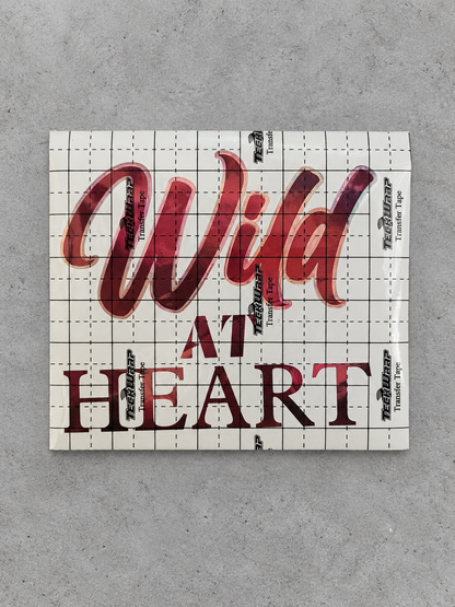 Wild at Heart vinyl decal in wine red with rose gold outline under transfer tape on grey concrete